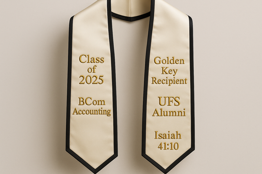 Cream graduation stole with black trimming, with CLass of 2025, Bcom Accounting, Golden key recipient, UFS Alumni and Isaiah 41:10 embroided on it